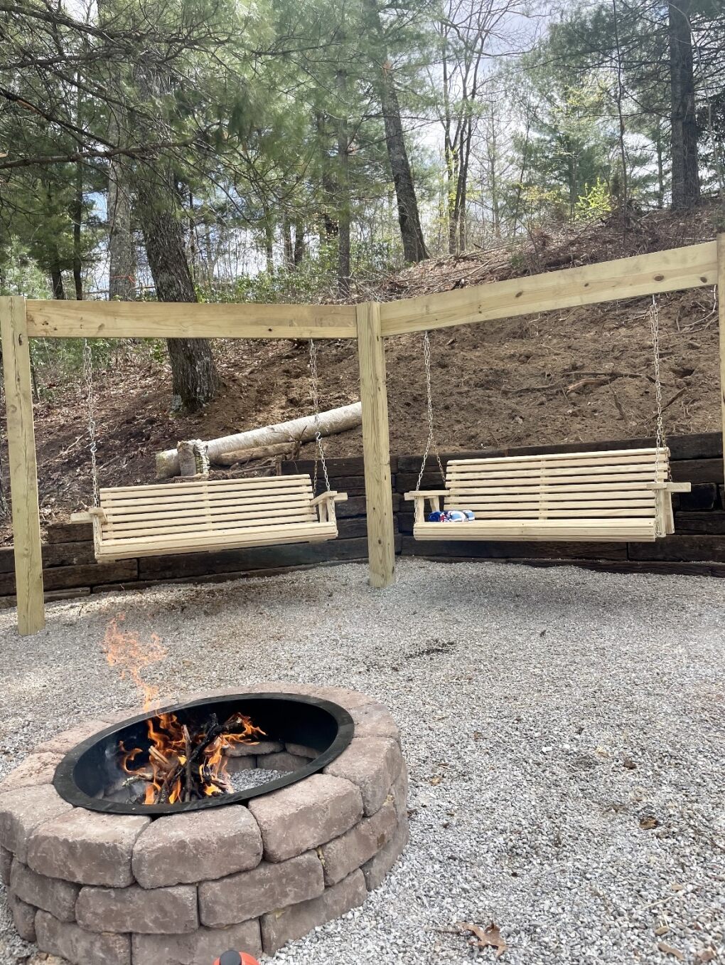 Timber swing structure with stone fire pit on gravel pad