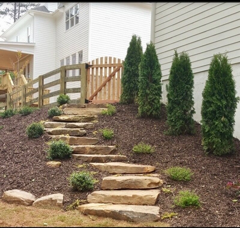 Natural flat stone steps with arborvitae and mulch beds